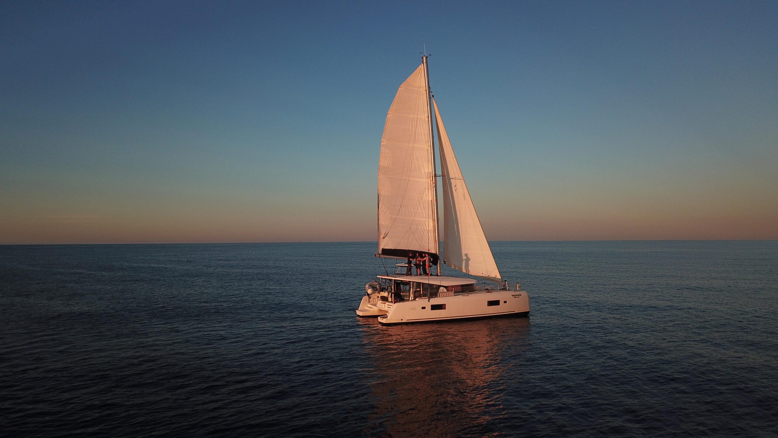 White Lagoon 42 catamaran Laurencia seen from the side near a rocky shoreline